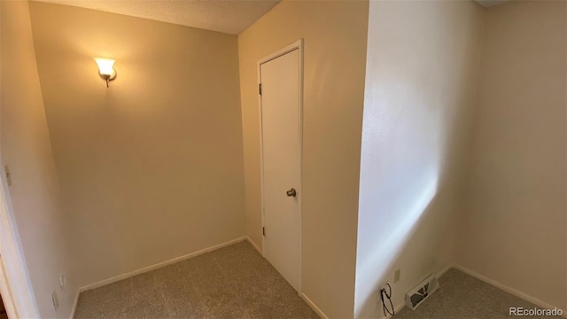 corridor with visible vents, a textured ceiling, baseboards, and carpet floors