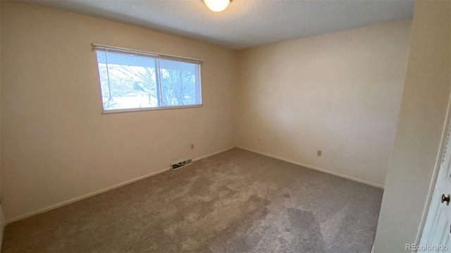 carpeted spare room with visible vents and baseboards