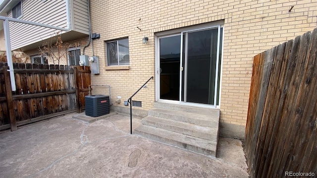 exterior space with cooling unit, a patio, brick siding, and fence