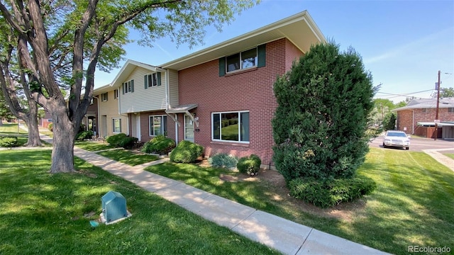 view of property with a front lawn and brick siding