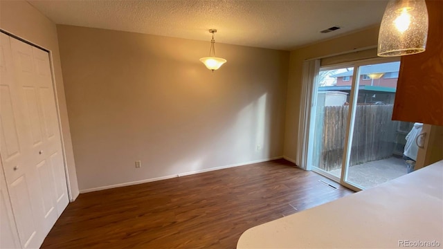 interior space with visible vents, a textured ceiling, baseboards, and wood finished floors