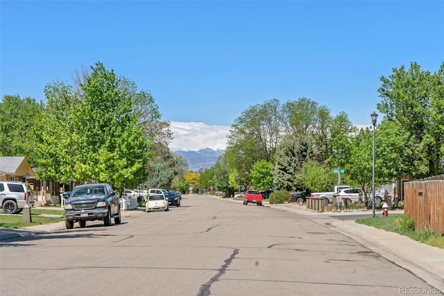 view of asphalt street with sidewalks, curbs, and street lighting