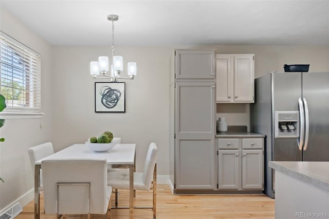 dining area featuring a chandelier, light wood finished floors, and baseboards
