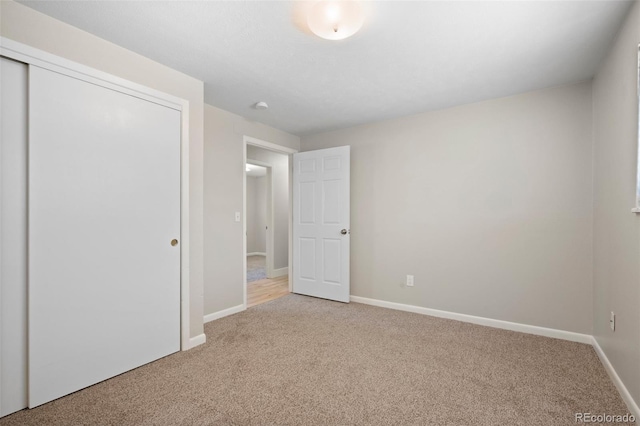unfurnished bedroom with carpet flooring, baseboards, and a closet