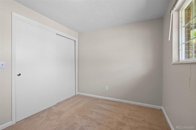 unfurnished bedroom with carpet floors, a closet, and baseboards