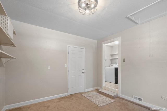 unfurnished room with washer / clothes dryer, attic access, light colored carpet, and baseboards