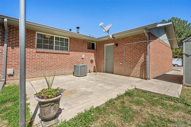 rear view of house with brick siding and a patio