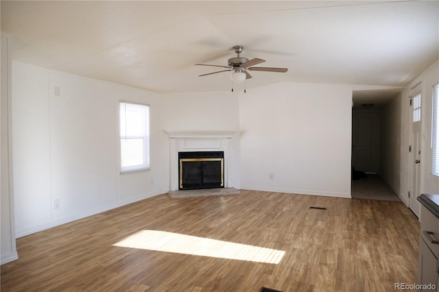 unfurnished living room with baseboards, a ceiling fan, a glass covered fireplace, and light wood-style flooring