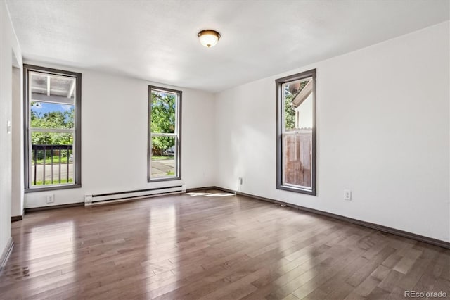 646 Maple St, Colorado Springs, CO 80903 - empty room featuring a baseboard heating unit, healthy amount of natural light, and wood finished floors