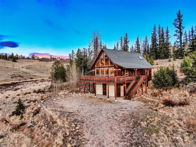 back of property featuring a wooden deck, a garage, stairs, and driveway