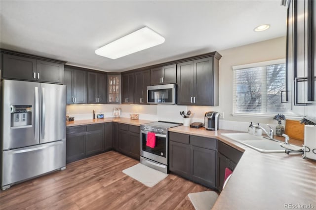 kitchen featuring dark brown cabinets, dark hardwood / wood-style flooring, sink, and appliances with stainless steel finishes