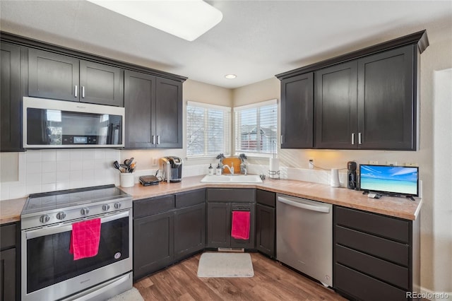 kitchen with decorative backsplash, hardwood / wood-style flooring, sink, and appliances with stainless steel finishes