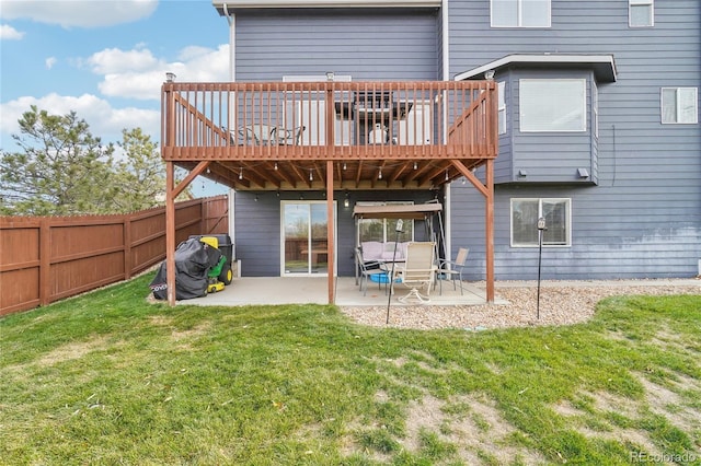 back of house featuring a lawn, a wooden deck, and a patio