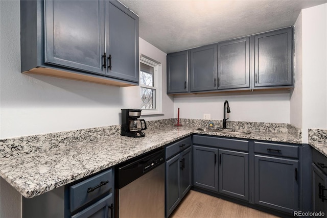 kitchen featuring light wood-style floors, a sink, a textured ceiling, light stone countertops, and dishwasher