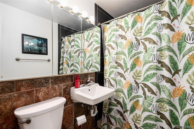 bathroom featuring a shower with curtain, a sink, toilet, and tile walls