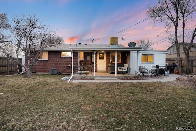 back of property featuring a yard, fence, central AC unit, and a patio