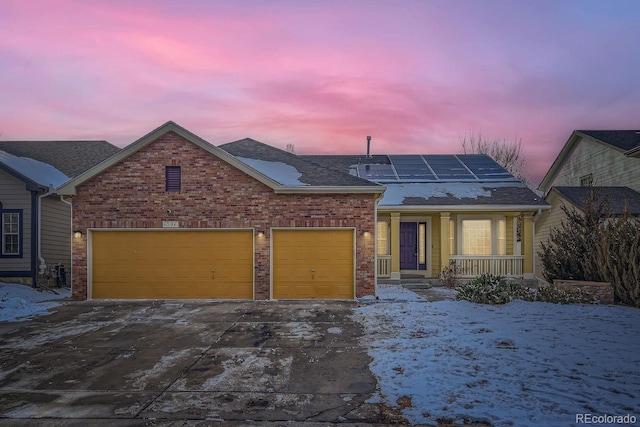 view of front facade featuring driveway, brick siding, an attached garage, and roof mounted solar panels