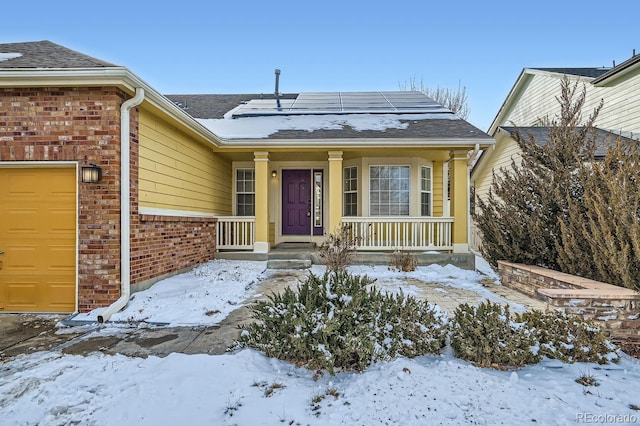 snow covered property entrance with a garage and brick siding