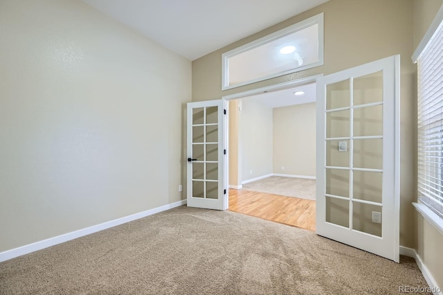 carpeted empty room featuring french doors and baseboards