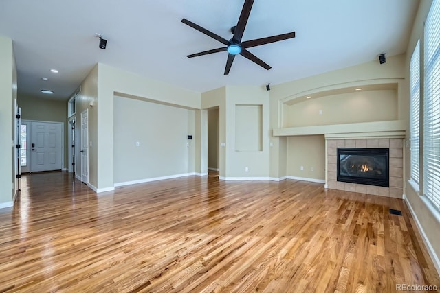 unfurnished living room featuring light wood-type flooring, baseboards, visible vents, and a tiled fireplace