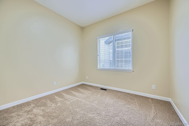 spare room with carpet flooring, visible vents, and baseboards