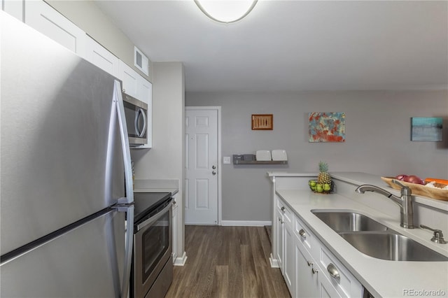 kitchen with a sink, appliances with stainless steel finishes, light countertops, white cabinetry, and dark wood-style floors