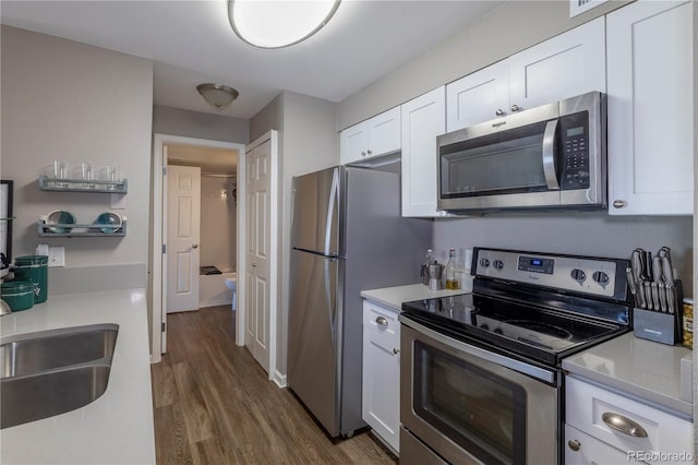 kitchen featuring a sink, dark wood finished floors, white cabinetry, light countertops, and appliances with stainless steel finishes