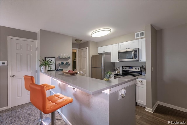 kitchen with a kitchen bar, visible vents, appliances with stainless steel finishes, and baseboards
