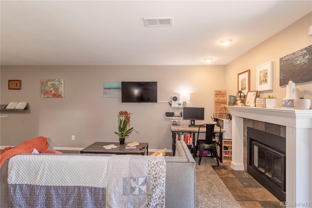 living room with baseboards, a tile fireplace, and visible vents