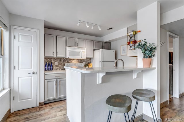 6711 S Ivy Way Unit A2, Centennial, CO 80112 - kitchen featuring white appliances, a kitchen bar, light countertops, decorative backsplash, and a peninsula