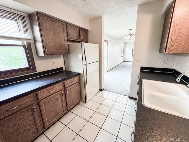1700 S 6th Ave, Sterling, CO 80751 - kitchen featuring freestanding refrigerator, dark countertops, a sink, a chandelier, and light tile patterned floors