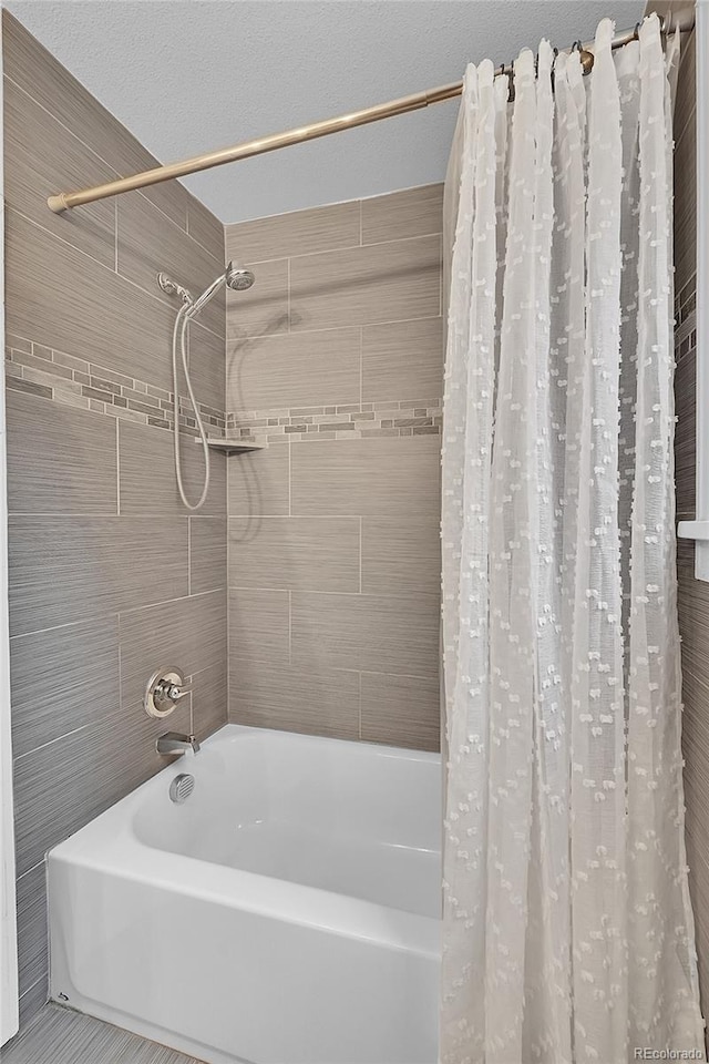 bathroom with shower / bathtub combination with curtain, a textured ceiling, and tile walls