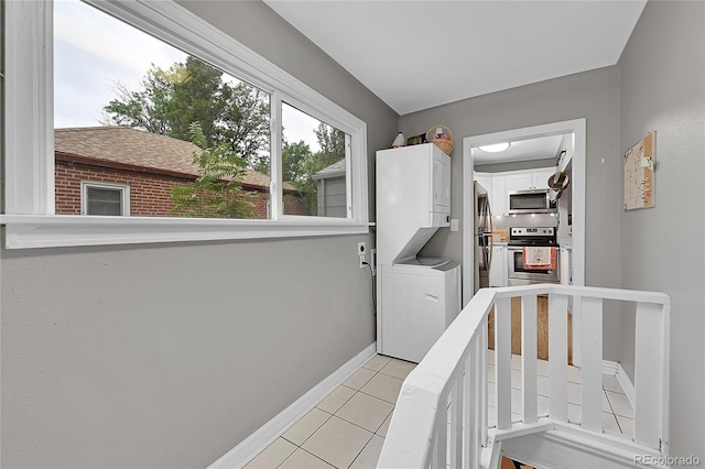 interior space featuring stacked washer and dryer, light tile patterned flooring, and cabinets