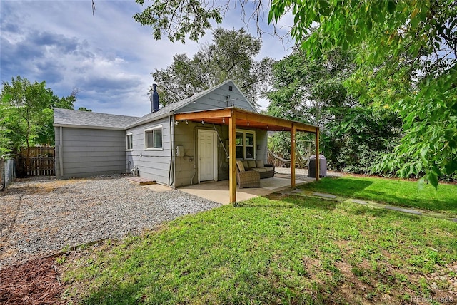 back of property with gravel driveway, a yard, fence, and a patio