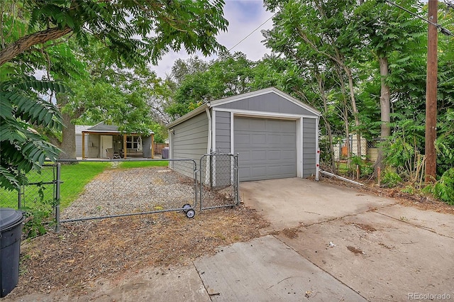 detached garage featuring a gate, fence, and concrete driveway