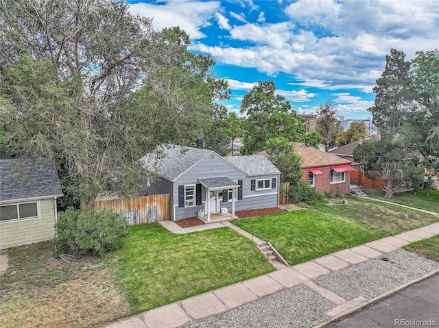 view of front of home with a front lawn, roof with shingles, and fence