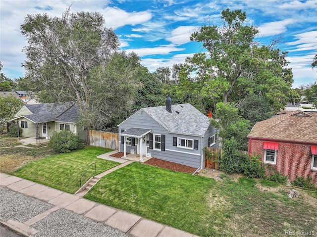 view of front of home with roof with shingles, fence, a chimney, and a front lawn