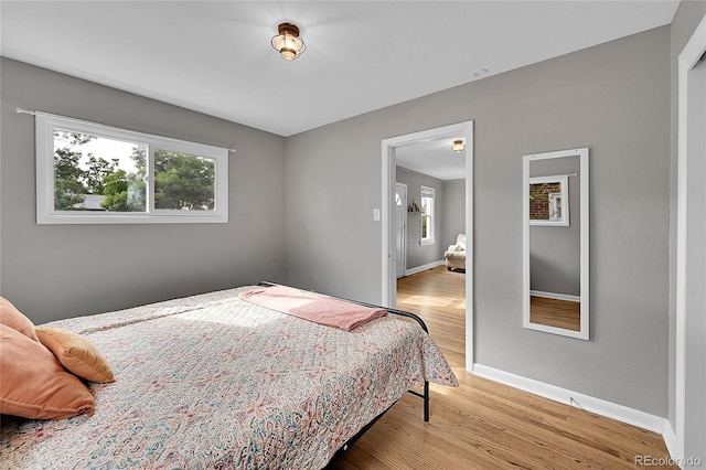 bedroom featuring multiple windows, baseboards, and wood finished floors