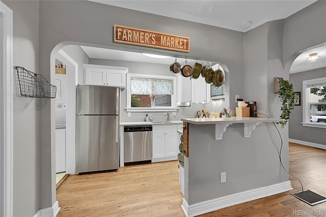 kitchen featuring appliances with stainless steel finishes, arched walkways, and white cabinets