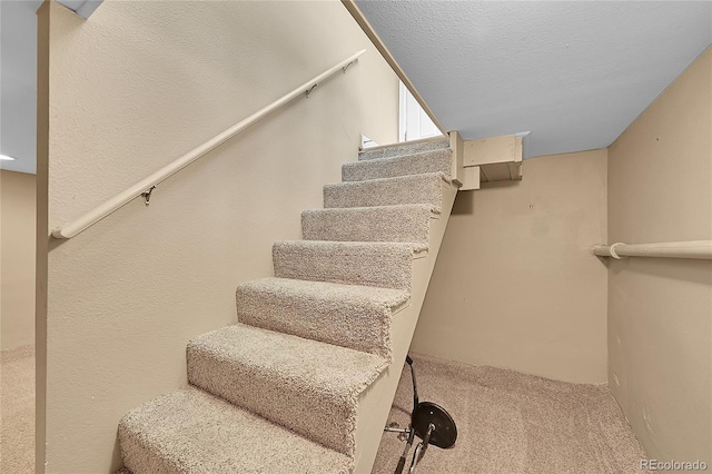 staircase with carpet and a textured ceiling