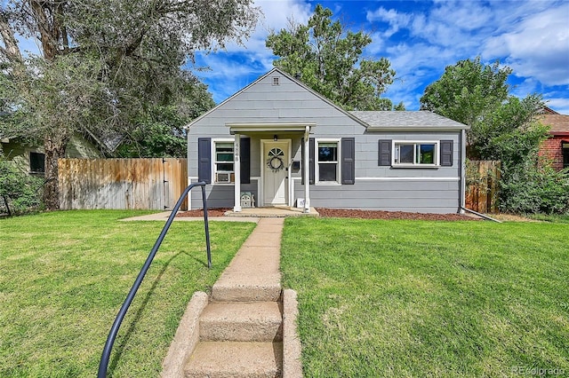 bungalow-style home featuring fence, a front lawn, and roof with shingles