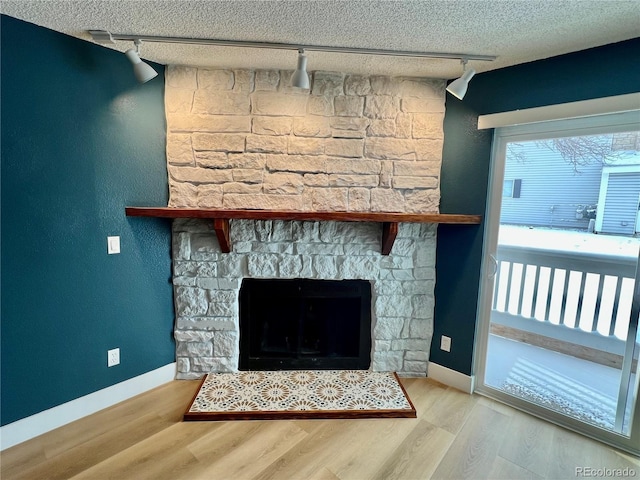 room details featuring hardwood / wood-style flooring, rail lighting, a textured ceiling, and a fireplace