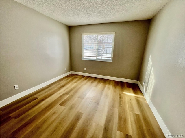 unfurnished room with a textured ceiling and light hardwood / wood-style flooring