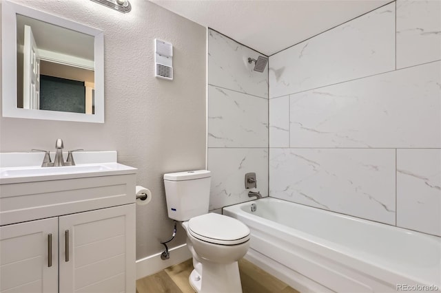 full bath with wood finished floors, vanity, a textured wall, shower / washtub combination, and toilet