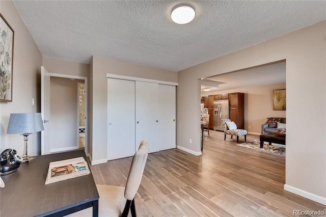 home office with light hardwood / wood-style floors and a textured ceiling