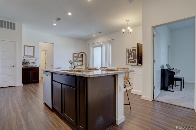 kitchen featuring decorative light fixtures, sink, an inviting chandelier, a kitchen island with sink, and dark hardwood / wood-style flooring