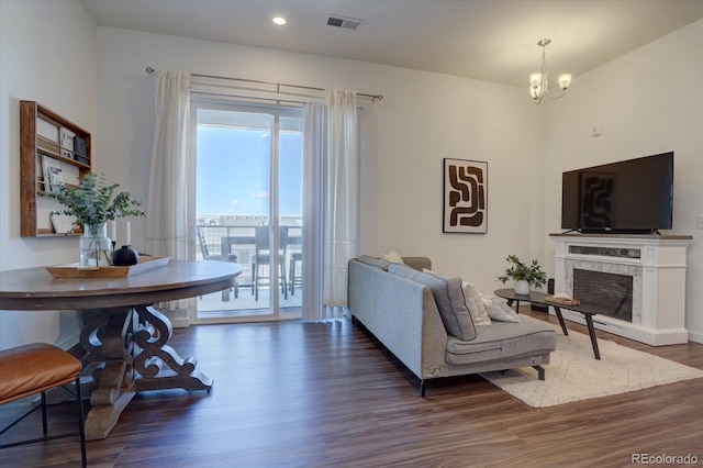 living room featuring dark hardwood / wood-style flooring, a premium fireplace, and a notable chandelier