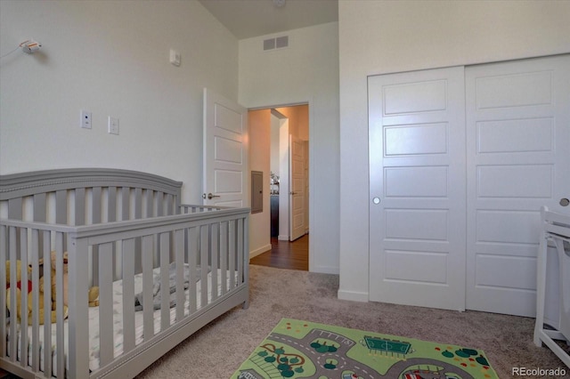 bedroom featuring a closet, light carpet, and a crib