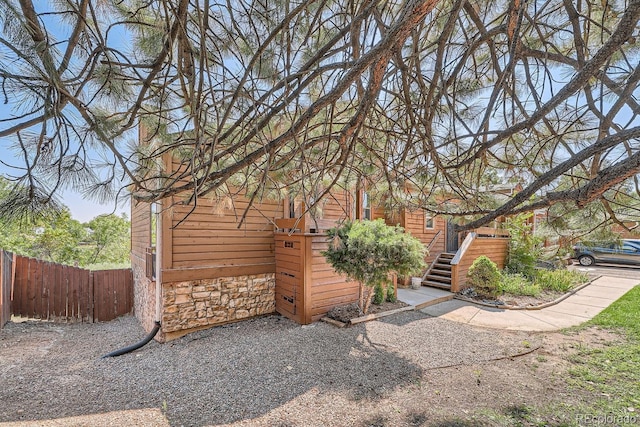 view of home's exterior with stone siding and fence