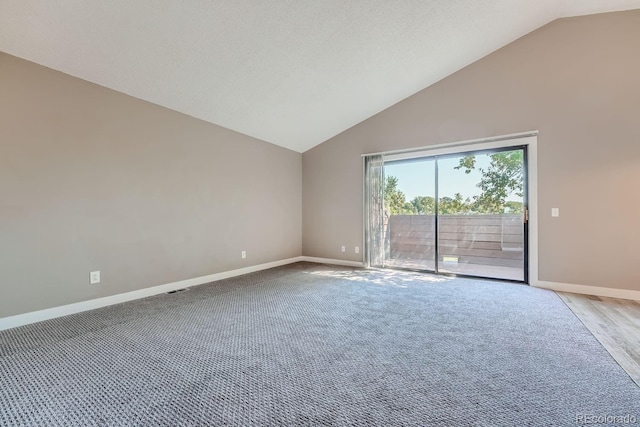 carpeted spare room featuring baseboards and high vaulted ceiling